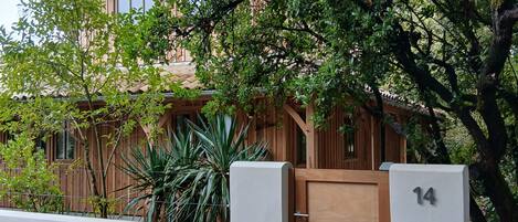 A residential building with a wooden gate, number 14, and a well-maintained garden with various plants.