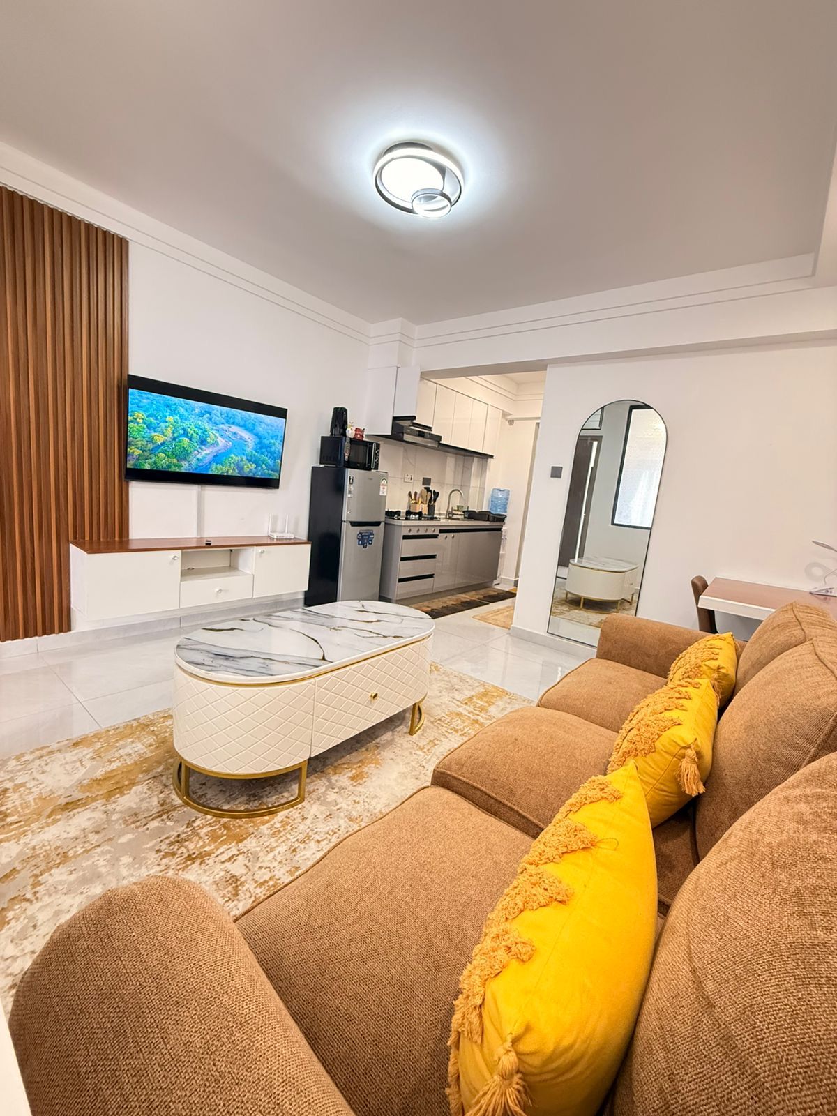 Een moderne woonkamer met een bank, een poef en een flatscreen televisie.