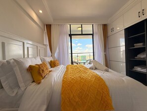 Ett hotellrum med en säng, en garderob och utsikt över staden genom ett fönster.