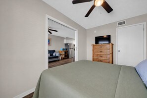 A bedroom with a bed, a dresser, a ceiling fan, and a television. - The Surf Shack | Gulf Shores Getaway (Gulf Shores)