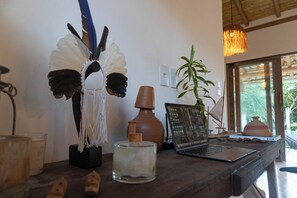 Ein Holztisch mit einem Laptop, einem dekorativen Vogel, einer Pflanze und einer Vase mit einer Kerze.
