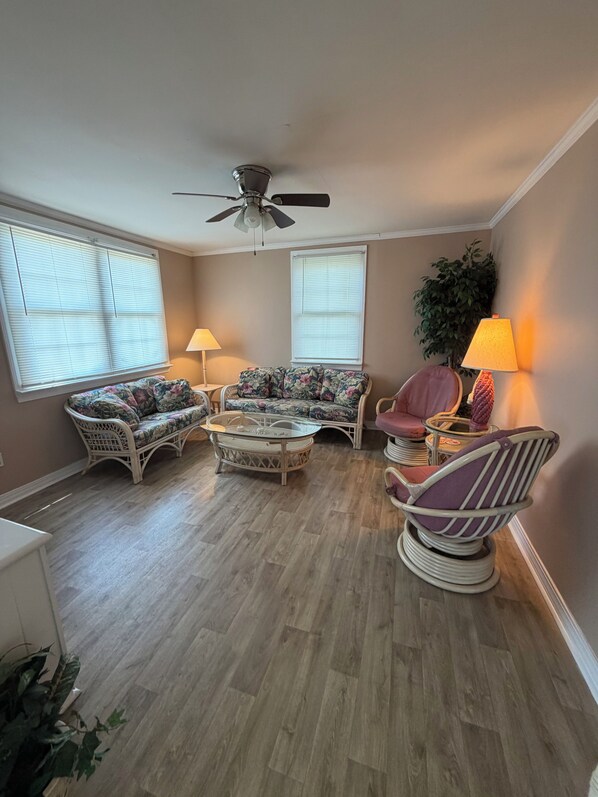 A living room with a ceiling fan, two sofas, a coffee table, and two lamps.