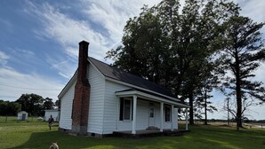 A single-story house with a chimney, a porch, and a grassy yard.