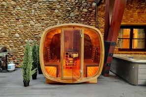 Eine Holzhütte mit bogenförmigem Äußeren, einem Whirlpool und einer Wand aus Stein im Hintergrund.