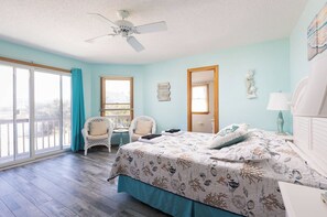 Ein Schlafzimmer mit Bett, Stuhl, kleinem Tisch und Deckenventilator.