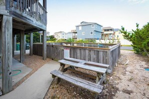 Eine Holzterrasse mit Picknicktischen, einem Poolbereich und Blick auf Wohnhäuser.