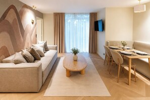 A modern living room with a sofa, a dining table set for two, and a TV mounted on the wall. - TheBlueStay 353 - Stunning Apartment A/C Paris 11 (Paris)