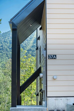 A building with a number '37A' on the side, a metal structure, and a view of a forested hillside. - Spa-Aventure | Massif du Sud (Saint-Philémon)