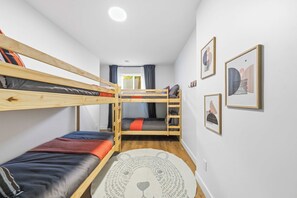 A bunk bed room with a window, a rug, and framed pictures on the wall. - Spa-Aventure | Massif du Sud (Saint-Philémon)