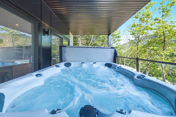 A hot tub with a view of trees and a modern building in the background.