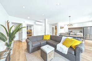 A modern living room with a grey sectional sofa, a small ottoman, and a potted plant.