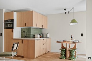 Eine moderne Küche mit Holzausstattung, einem Einbauofen und einem Essbereich mit rundem Tisch und Hockern.