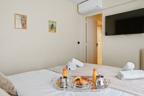 Ein Hotelzimmer mit einem Bett, einem Tablett mit Frühstücksgegenständen und einem an der Wand befestigten Fernseher.