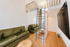 A modern living room with a green sofa, a circular rug, and a metal ladder leading to a loft area. - TheBlueStay 357 - Apt near the Eiffel Tower - A/C (Paris)