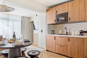 Eine moderne Küche mit Holzschränken, einem eingebauten Ofen und einem Essbereich mit rundem Tisch und Stühlen.