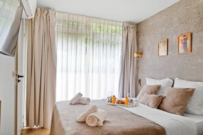 Ein Hotelzimmer mit einem Bett, einem Tablett mit Frühstücksgebäck und einem großen Fenster mit Vorhängen.
