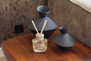 Ein Holztisch mit drei schwarzen Vasen und einer Flasche von Blossom & Mignonette Parfüm.