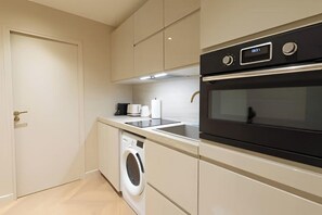A compact kitchen with a washing machine, a built-in oven, and a coffee maker. - TheBlueStay 356 - Stunning Apartment A/C Paris 11 (Paris)