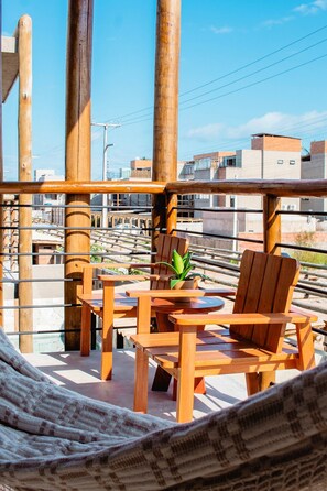 A wooden deck with a table and chairs, a hammock, and a potted plant. - Maravilhosa Casa Piscina Privativa (Sao Miguel dos Milagres)
