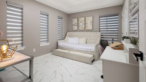 Ein Schlafzimmer mit Bett, Schreibtisch und Deckenventilator.