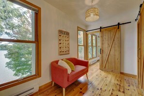 A room with a red sofa, large windows, a wooden floor, and a 'Types of Deer' poster. - Pagaie et Pyjama - Saint-Étienne-de-Bolton (Saint-Étienne-de-Bolton)