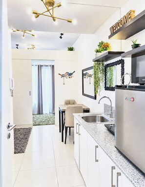 Una cocina moderna con un refrigerador de acero inoxidable, un lavamanos y un comedor con mesa y sillas.