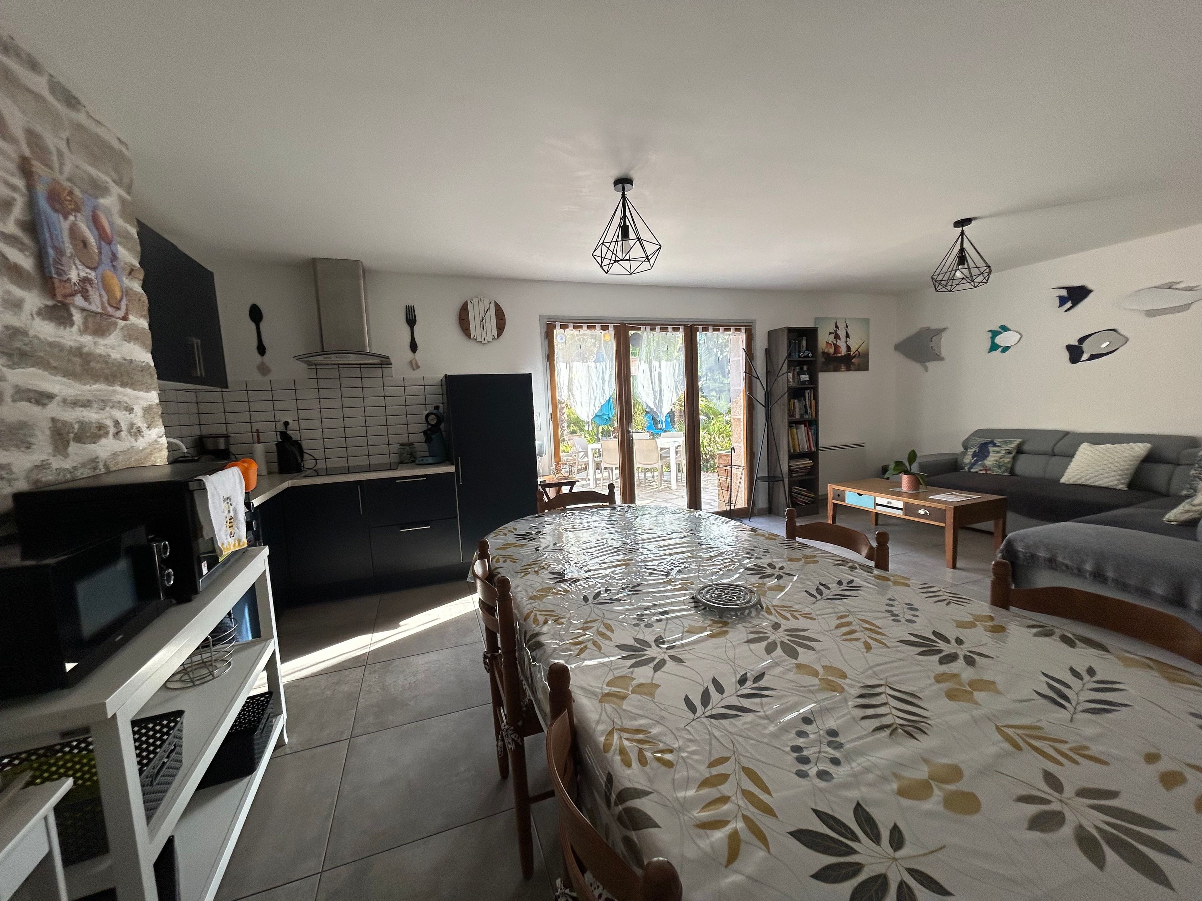 Una cocina moderna con comedor, sofá y vistas a través de un ventanal.