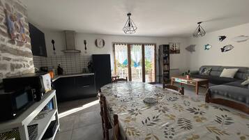 Una cocina moderna con comedor, sofá y vistas a través de un ventanal.