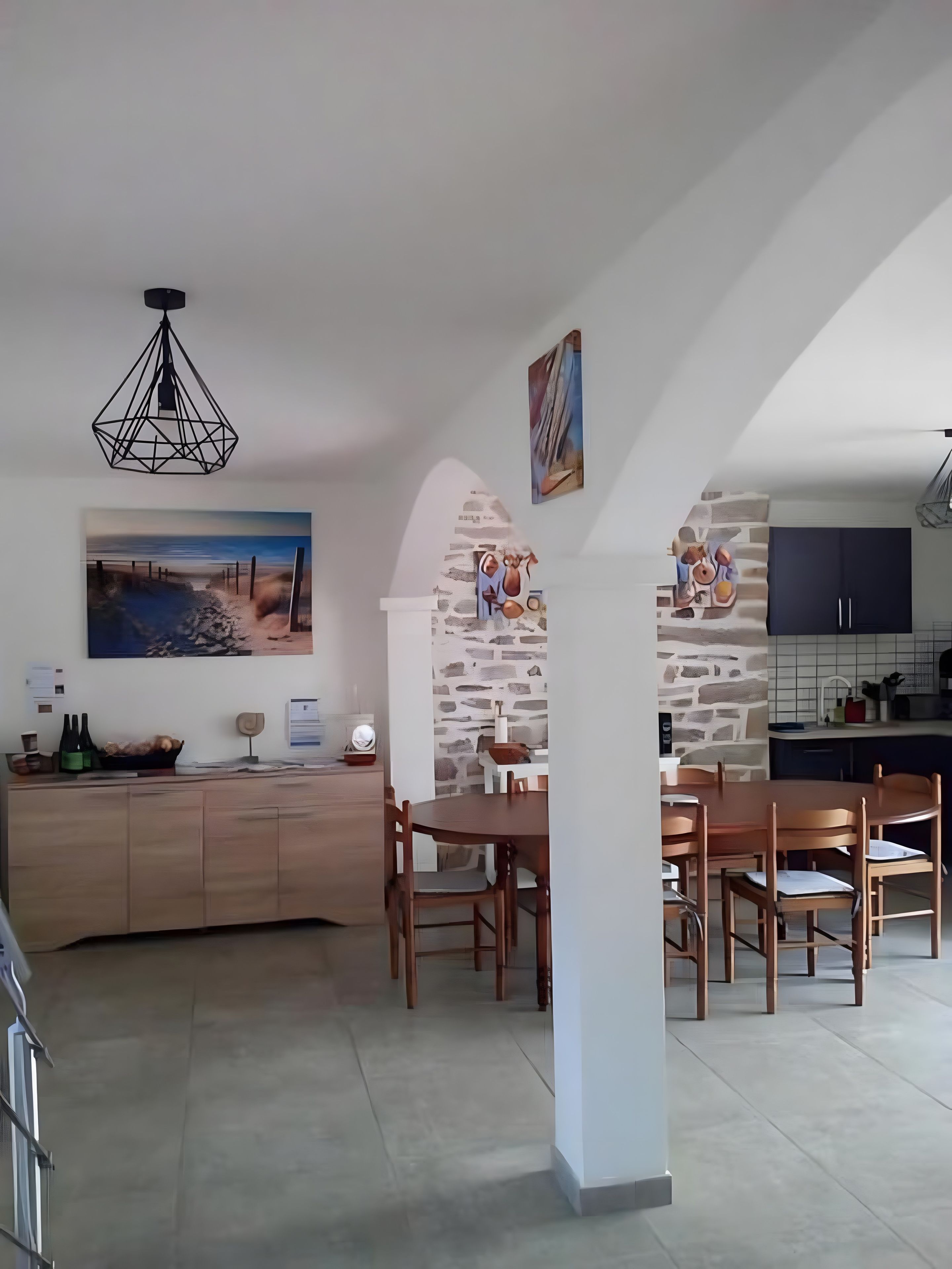 Una cocina moderna con pared de piedra, mesa de comedor de madera y una lámpara colgante.