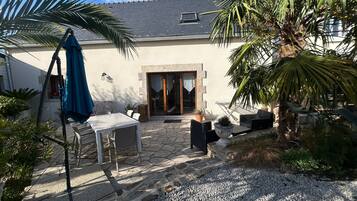 Une terrasse avec des meubles d’extérieur, un sol en pierre et un palmier.
