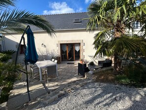 Un patio con mobiliario exterior, piso de piedra y una palmera.