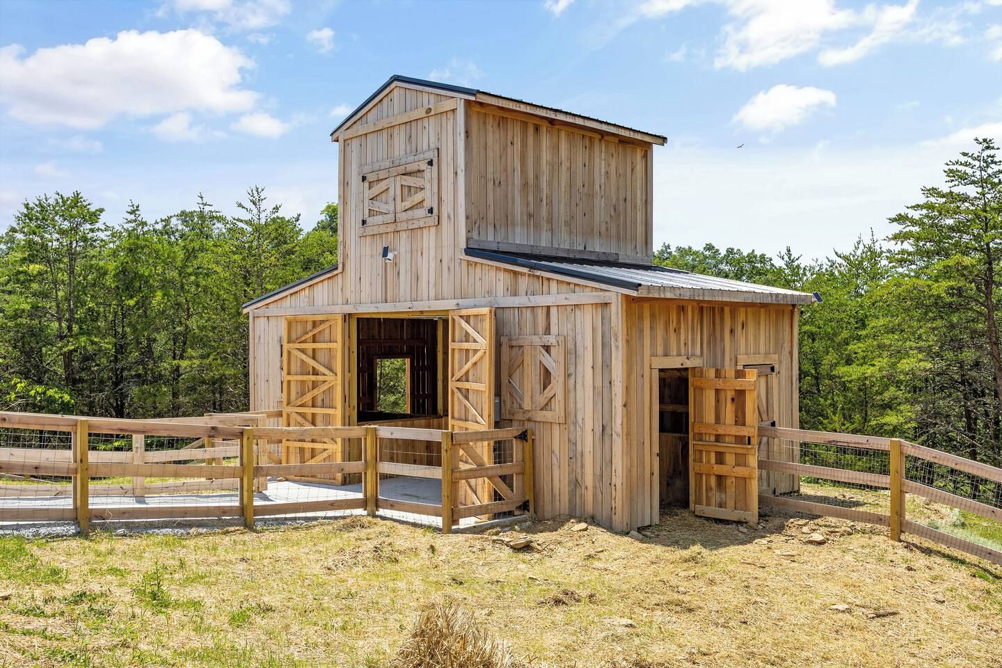 A wooden structure with a ramp leading to an open door, surrounded by a wooden fence.