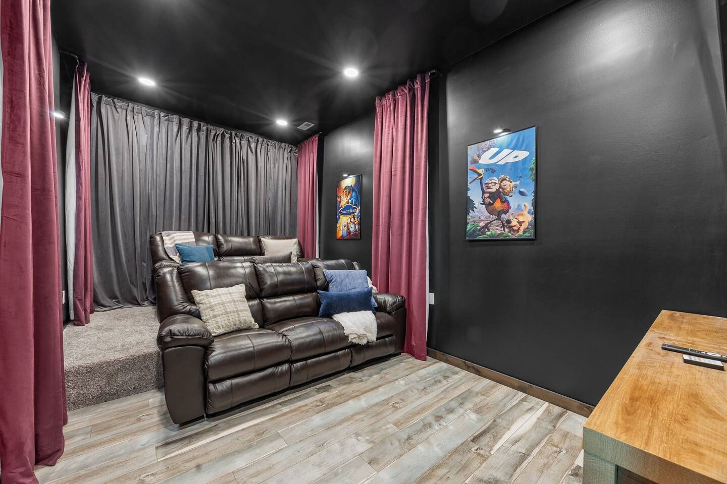 Ein Heimkinozimmer mit einer Ledersofa, roten Vorhängen und einem Poster an der Wand.