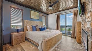 A bedroom with a large bed, wooden headboard, and a stone wall with a fireplace.