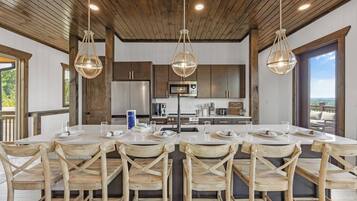 Un comedor amplio con una larga mesa dispuesta para varias personas, sillas de madera e iluminación colgante.