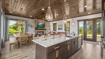A spacious kitchen with a large island, wooden cabinets, and pendant lighting.