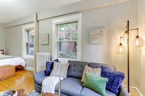 A room with a grey sofa, a white radiator, and a window with a view of a brick building. - Belltown Couples Retreat with Easy Access to Lumen Field (Seattle)