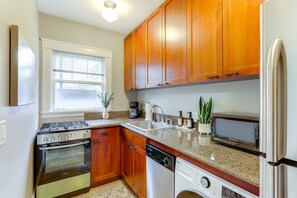 A kitchen with wooden cabinets, a stove, a dishwasher, and a refrigerator. - Belltown Couples Retreat with Easy Access to Lumen Field (Seattle)