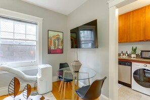 A modern kitchen with a built-in oven, a dining area with a glass table, and a large window with a view of the cityscape. - Belltown Couples Retreat with Easy Access to Lumen Field (Seattle)