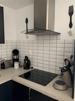 Et moderne køkken med sort induktionskogeblad, kaffemaskine, brødrister og elkedel.