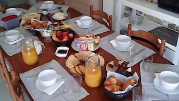 Mesa lista con platos, vasos y diversos alimentos, sugiriendo un momento para comer.