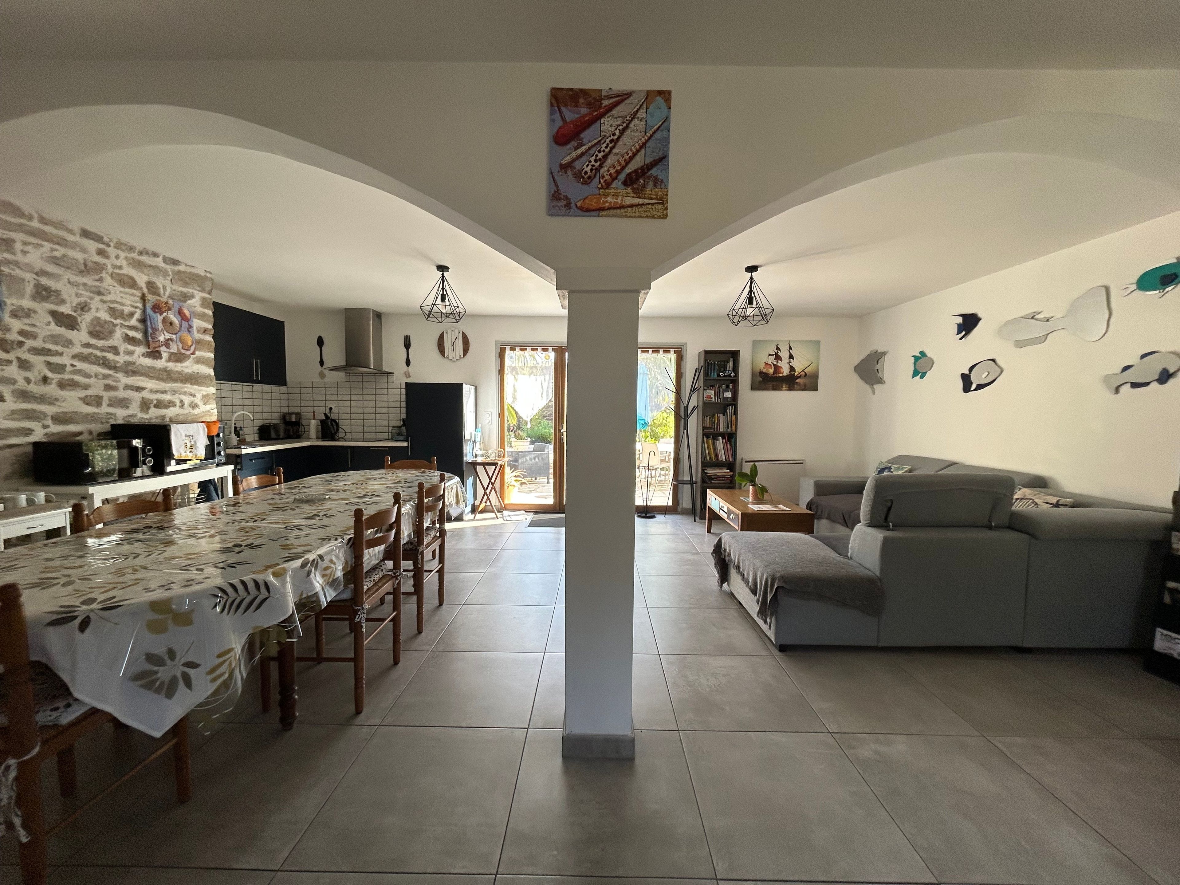 Amplia sala de estar con mesa de comedor, cocina y sofá gris.