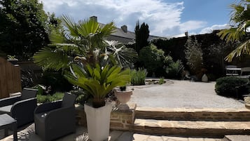 Un patio con mobiliario exterior, plantas en macetas y un camino de piedra.
