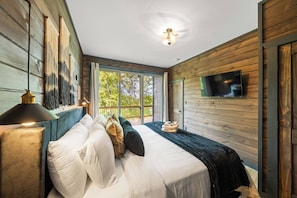 Ein Schlafzimmer mit einem Bett, einem Fernseher und Blick ins Freie.