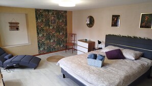 A bedroom with a bed, a desk, a chair, and a wall with a tropical wallpaper. - The Great Cozy Safari (Petersbach)