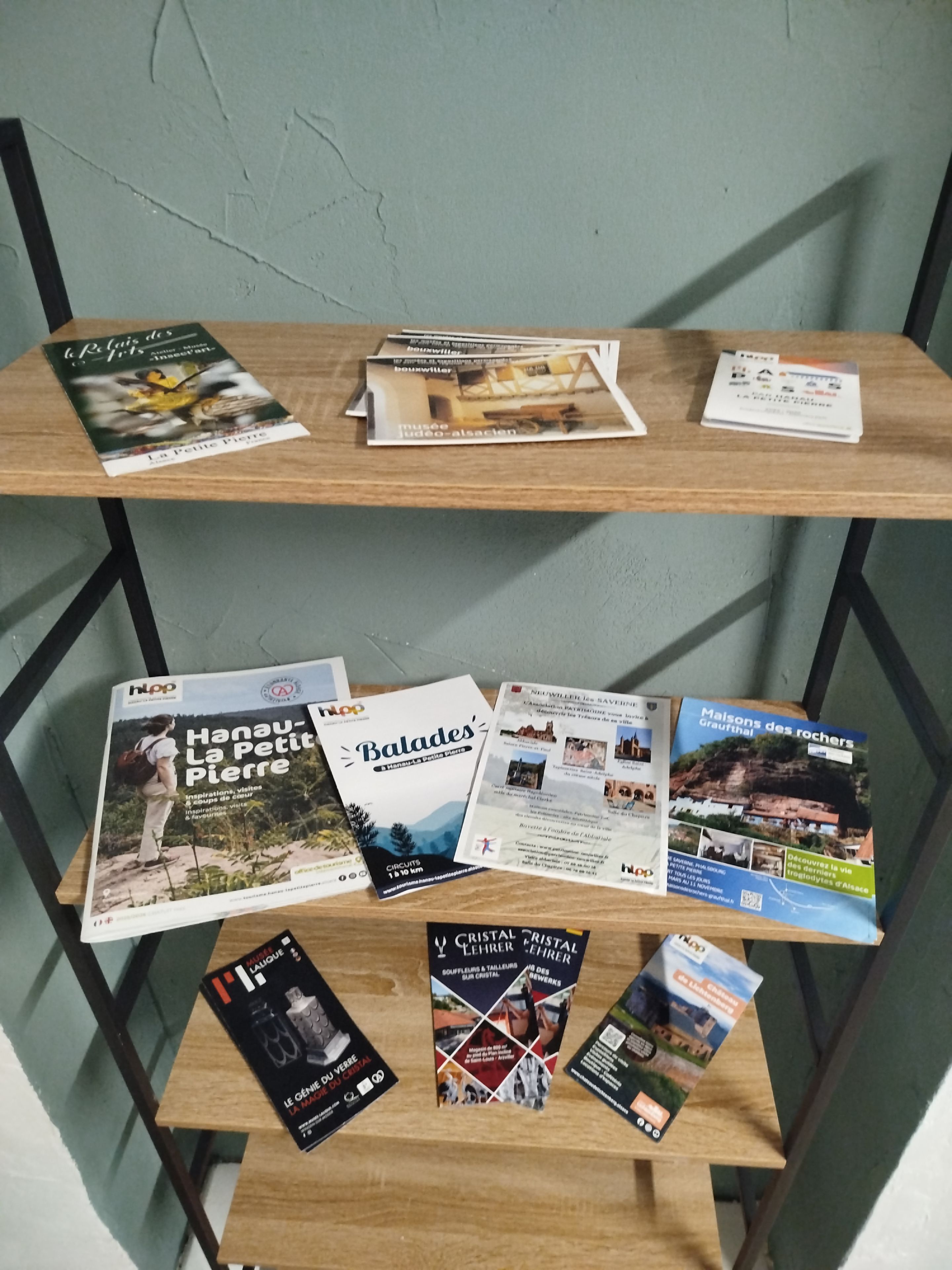 Une étagère en bois où sont posées des brochures et des guides de voyage.