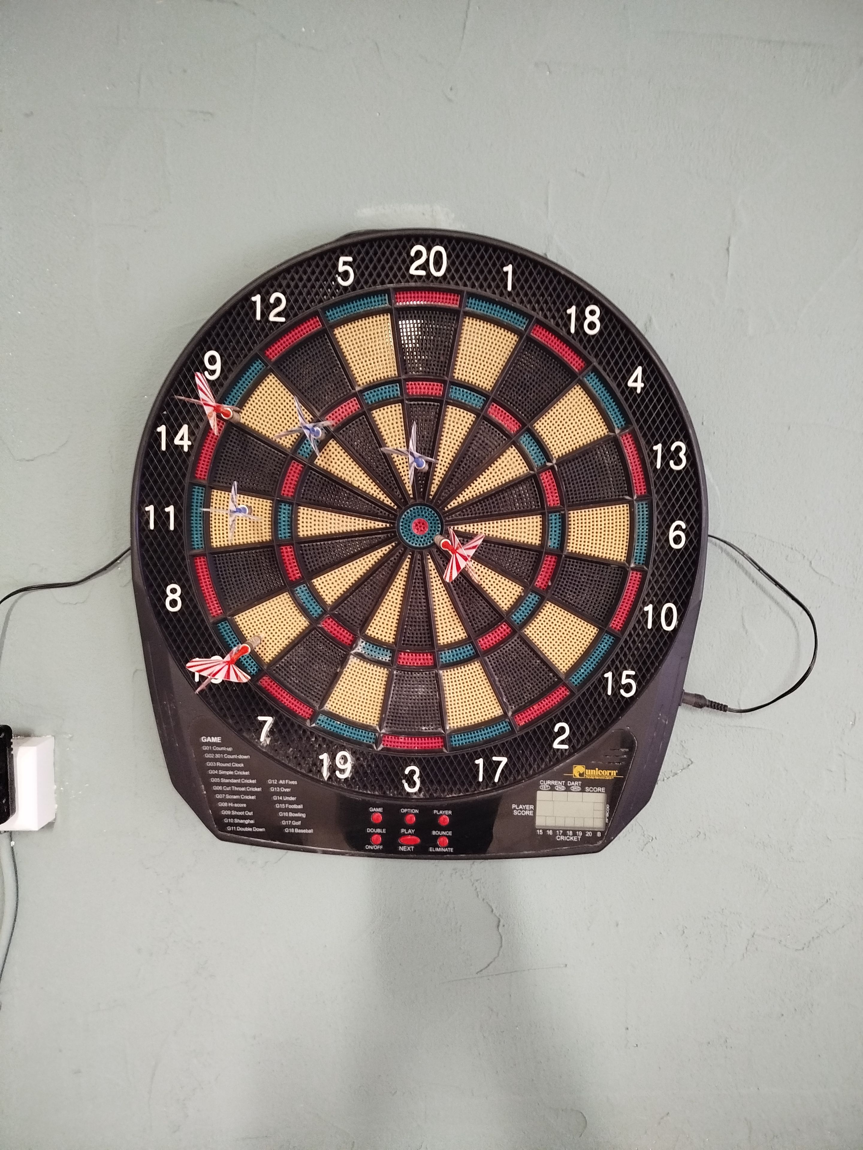 Een dartbord bevestigd aan een muur, met een digitale scorebord eronder.