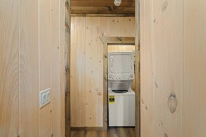 A laundry room with a stacked washer and dryer, wooden walls, and a visible electrical outlet. - VIEWS-Luxe-Beach Access-Pets-Games-Hot Tub (Sevierville)