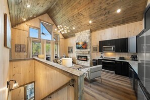 A wooden interior with a kitchen, dining area, and a fireplace. - VIEWS-Luxe-Beach Access-Pets-Games-Hot Tub (Sevierville)