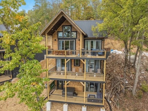 A multi-story wooden building with balconies, large windows, and a view of trees. - VIEWS-Luxe-Beach Access-Pets-Games-Hot Tub (Sevierville)